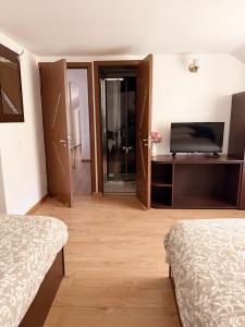 a hotel room with two beds and a television at Pensiunea Laura in Chişcău