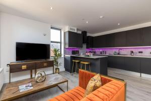 a living room with an orange couch and a kitchen at Sussex House 20 - Artistic Luxe 1 Bed Apartment in Horsham