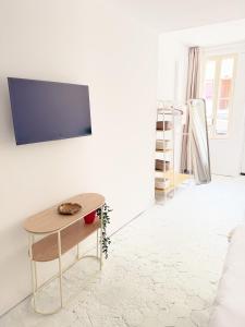 a living room with a table and a tv on a wall at Atelier Marguerite, plain-pied au cœur de Tonnerre in Tonnerre