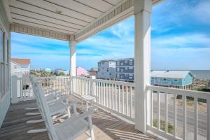 a porch with two chairs and a view of the ocean at Wait N Sea by Oak Island Accommodations in Oak Island