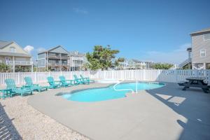 a swimming pool with blue chairs and a picnic table at Wait N Sea by Oak Island Accommodations in Oak Island
