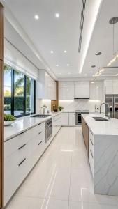 a white kitchen with white cabinets and a large window at Paradise View Villas in Malindi