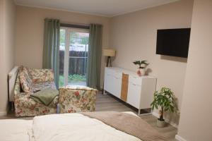 a bedroom with a bed and a chair and a television at Dahlmanns Pension am Park in Oranienbaum-Wörlitz