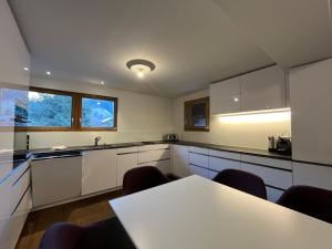 a kitchen with white cabinets and a table with chairs at Ferienlenk Mountain Village in Lenk