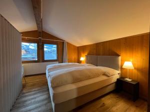 a bedroom with a large bed and two windows at Ferienlenk Mountain Village in Lenk