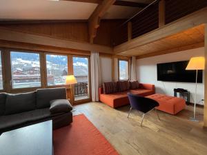 a living room with a couch and a television at Ferienlenk Mountain Village in Lenk