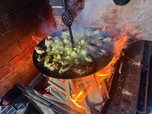 a pot of food cooking on a grill with flames at Horse Garden in Valea Groşilor