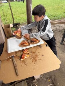 a young boy sitting at a table eating pizza at Horse Garden in Valea Groşilor