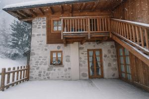 a house with a balcony and a deck in the snow at Chalet Dolomiti Trentino in Sant’Orsola