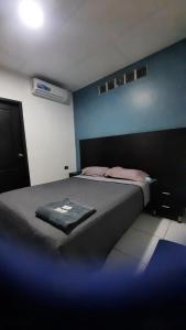 a bedroom with a bed with a blue wall at Hotel confort in Guayaquil
