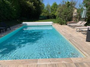 a swimming pool with blue water and a wooden deck at Cookie home in Dolomieux