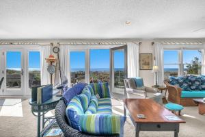 a living room with a blue couch and chairs and windows at Jonahs Whale by Oak Island Accommodations in Caswell Beach