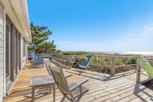 a deck with rocking chairs and the beach at Jonahs Whale by Oak Island Accommodations in Caswell Beach