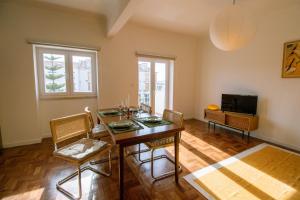 a dining room with a table and chairs and a television at Casa do Largo Ericeira in Ericeira