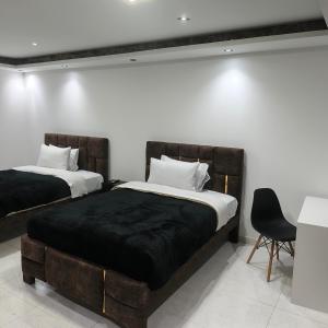 a bedroom with two beds and a chair at Hotel Gool De Guerron in Quito