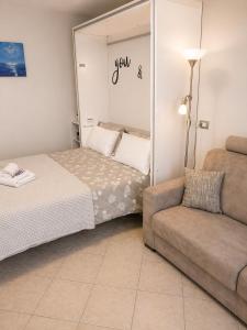 a small bedroom with a bed and a couch at Oxygen Riva del Garda Monolocale con Balcone e Bike Room in Riva del Garda