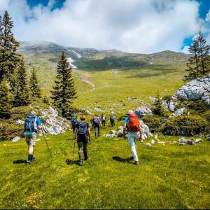 a group of people walking on a grassy hill at Serana Stays Classic Apartment with Private Bathroom, Free WiFi & Parking, Central Pejë in Peje