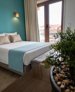 a bedroom with a bed and a potted plant at Hotel Areias Claras in Viana do Castelo