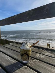 a drink sitting on a wooden bench at the beach at Hotel Areias Claras in Viana do Castelo