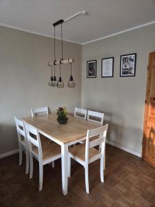 a dining room table with white chairs and a table and lights at Lüdde Stuv am Meer in Husum