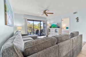 a living room with a large couch and a ceiling fan at Sand Between Stays in Orange Beach