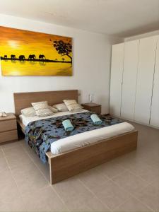a bedroom with a bed and a painting on the wall at Kasa n'areia, Praia Estoril in Sal Rei