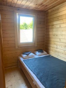 a bed in a wooden cabin with a window at Агрооселя Ростоки in Zhdanivka