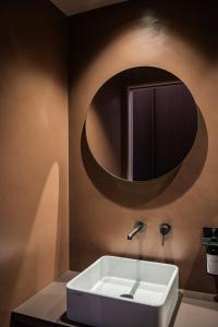 a bathroom with a sink and a round mirror at Agriturismo OPERA02 in Castelvetro di Modena +45 photos