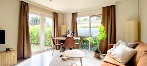 a living room with a table and some windows at Boshuisje Dille te Veluwe in Putten