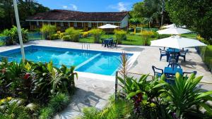 a pool with chairs and umbrellas in a yard at Finca Hotel La Herencia Cafetera in Montenegro