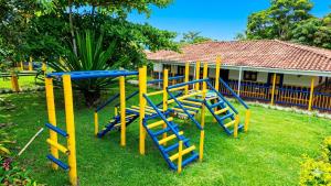 a playground with blue and yellow equipment in a yard at Finca Hotel La Herencia Cafetera in Montenegro