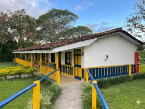 a small yellow and white building with a pathway to it at Finca Hotel La Herencia Cafetera in Montenegro +12 photos