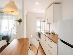 a kitchen with white cabinets and a wooden table at Flores in Málaga +19 photos