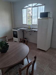 a kitchen with a table and a white refrigerator at Casa 2 quartos perto Centro Ipatinga e aeroporto in Santana do Paraíso