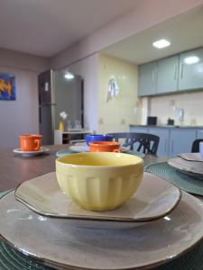 a yellow bowl sitting on a plate on a table at Studio chamorso - Cama Queen - AC - Garagem in Rondonópolis