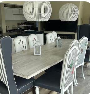 a dining room table with white chairs and white chandeliers at Casa refugio in Santa María