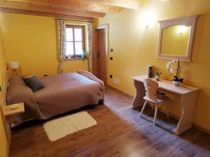 a bedroom with a bed and a desk and a mirror at Chalet Dolomiti Trentino in Sant’Orsola