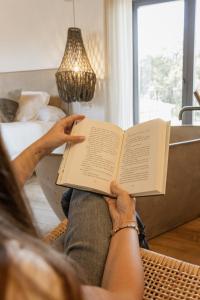 a woman sitting on a couch reading a book at Mas Escarrà in Caldes de Malavella