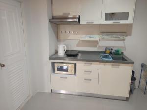 a small kitchen with white cabinets and a microwave at Pattaya Center Point Condo in Pattaya +5 photos