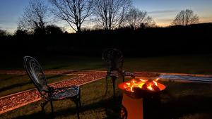 two chairs sitting next to a fire pit at Spinney Wood Glamping, Oak Hut in Bewdley