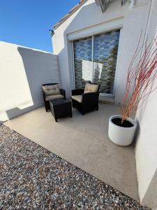 a patio with chairs and a plant in a pot at L'instant étoilé in Châteauneuf-lès-Martigues