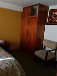 a bedroom with a bed and a chair and a cabinet at Cordelius Hotel in Puno