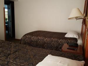 a hotel room with two beds and a table with a lamp at Cordelius Hotel in Puno