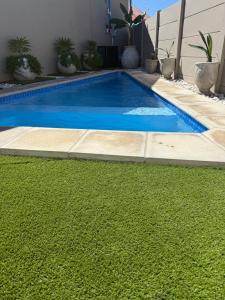 a swimming pool with green grass next to a house at Casa Bonheur in Windhoek