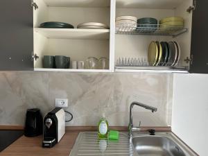 a kitchen counter with a sink and a shelf with dishes at Casa Serena in Baveno