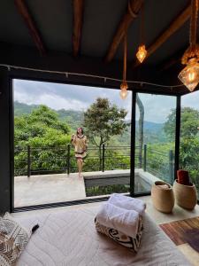 a woman standing in a room with a large window at Glamping Raíces in Manizales