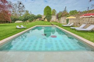a swimming pool in a yard with chairs and umbrellas at Verneuil la douce in Verneuil d'Avre et d'Iton