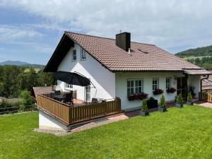 a white house with a balcony with an umbrella at Ferienhaus Heidi in Lam