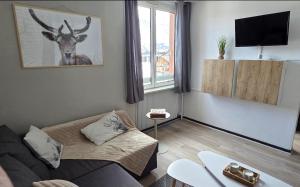 a living room with a couch and a deer on the wall at Appartement T1 Superdévoluy 6 personnes in Le Dévoluy
