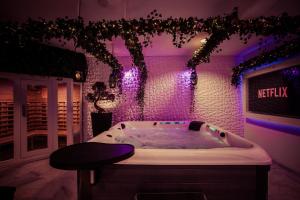 a jacuzzi tub in a room with purple lights at B&W Malina Jacuzzi Suite in Lelystad